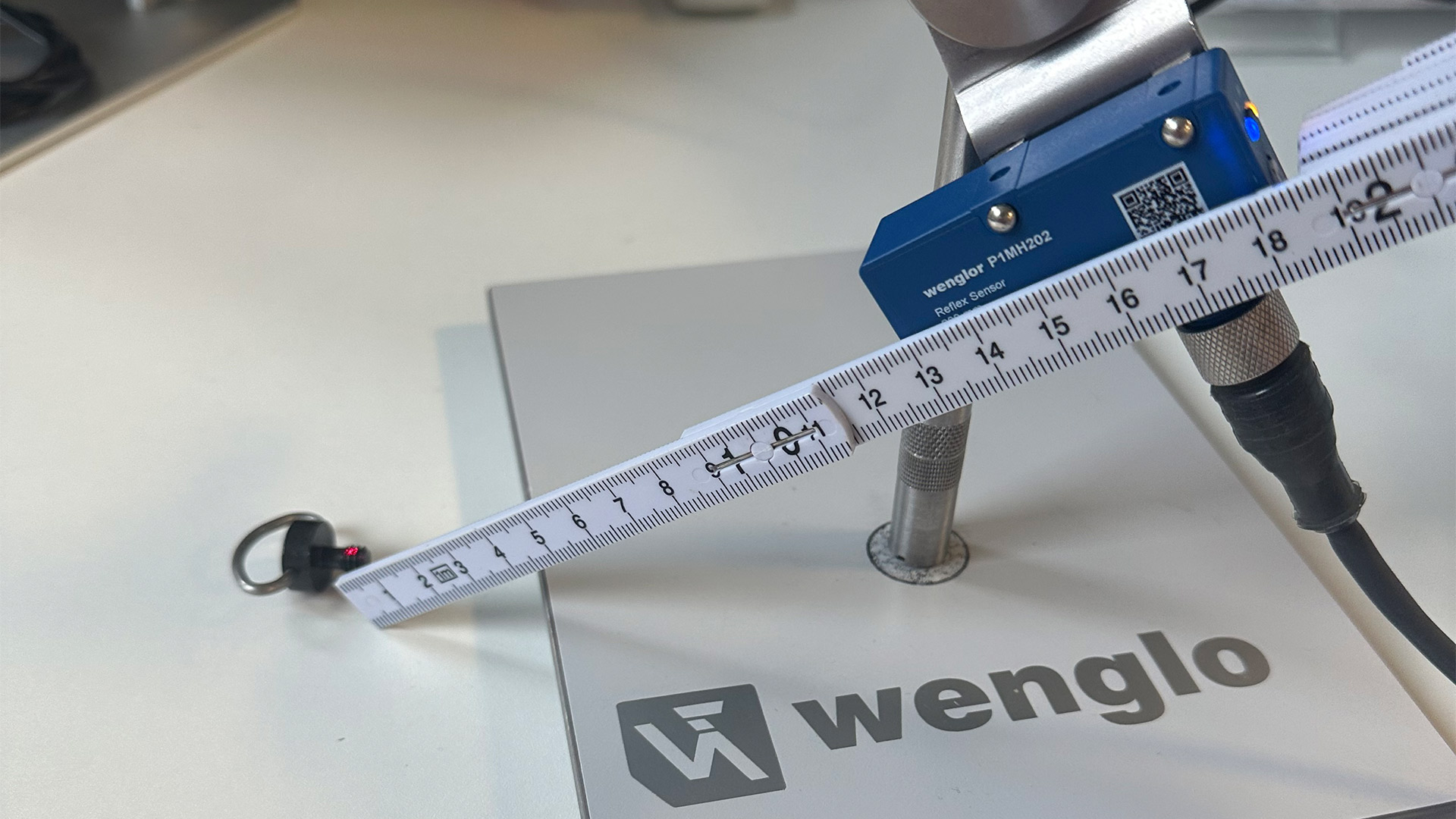 Preskusna nastavitev z laserskim refleksnim skenerjem P1MH202 za zaznavanje črnega navoja M6 na razdalji približno 135 mm.