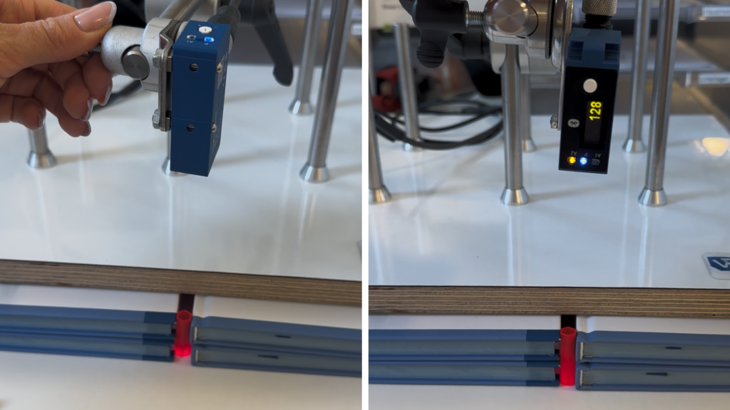 Ein Laser-Distanzsensor und ein Reflextaster sind nebeneinander montiert, beide Laserstrahlen gehen senkrecht nach unten durch ein kleines Rohr durch.