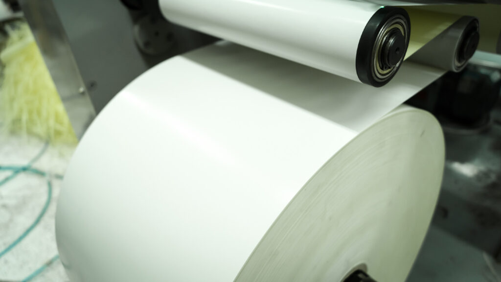 Kağıt ağ, endüstriyel üretim tesisindeki rulo rulolarının üzerinden geçiyor
